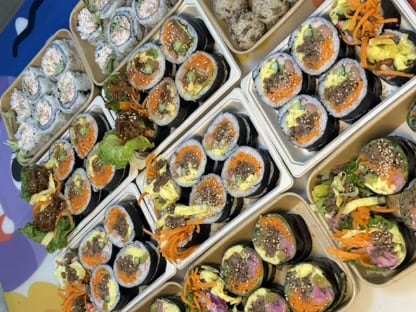 多盒不同口味紫菜包饭与牛肉饭团集中摆放的出餐现场